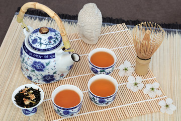 Jasmine tea with cherry blossom, stone Buddha head, teapot, cups, leaves and whisk on bamboo.  Also used in herbal medicine.