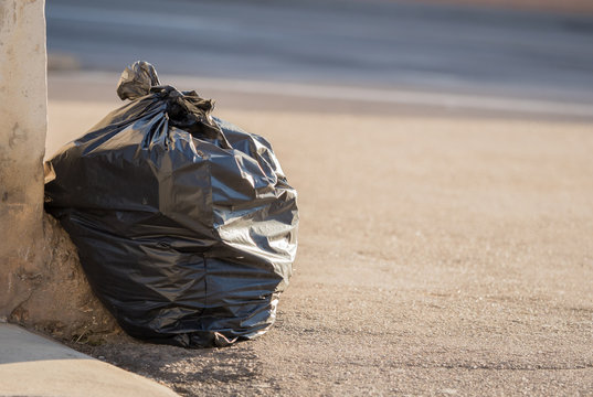 Black garbage bag lies on the road