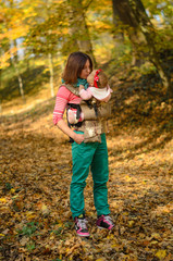 Mother carrying her baby daughter in ergonomic backpack for children