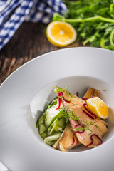 Fish trout fillet with cucumber salad and herb decoration. Fish with vegetable salad on plate in hotel or restaurant.