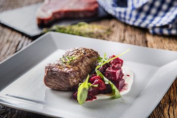 Beef steak with beetroot and herb decoration. Beef steak on plate in hotel or restaurant