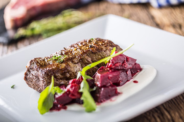 Beef steak with beetroot and herb decoration. Beef steak on plate in hotel or restaurant