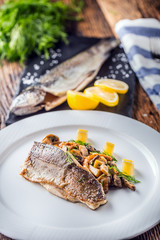 Fish trout with mushrooms and vegetable on plate in hotel or restaurant