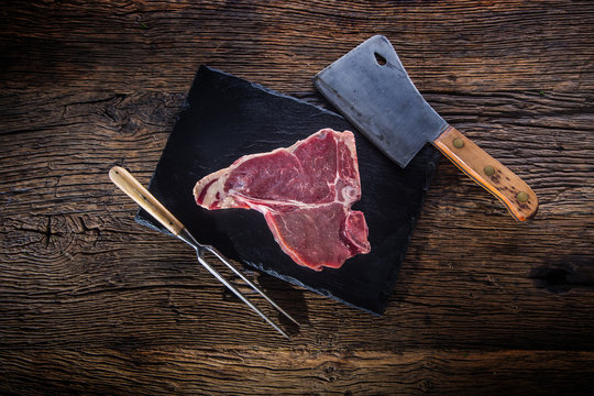 Beef steak T-bone. Raw beef steak T-bone on slate board with butcher and fork