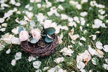 Obraz na płótnie Canvas Wedding rings on the grass and flower petals