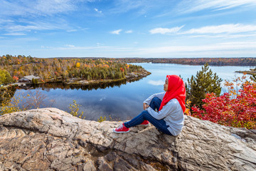 A muslim teenager enjoying view of a lake from top of the hill during fall season