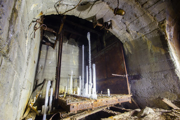 Fototapeta na wymiar Underground abandoned ore mine shaft tunnel gallery lift with ice stalagmites