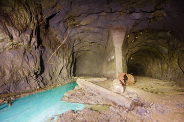 Underground abandoned ore mine shaft tunnel gallery with blue water