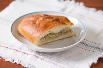 Fresh hot Russian pies with cabbage and meat. sliced pie on a plate - a traditional Russian dish