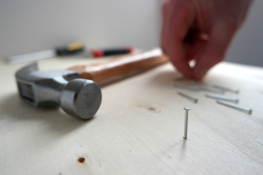 A man picking up nails and screws, with a hammer on home improvement construction site
