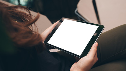 Mockup image of a woman holding black tablet pc with blank white screen in modern cafe