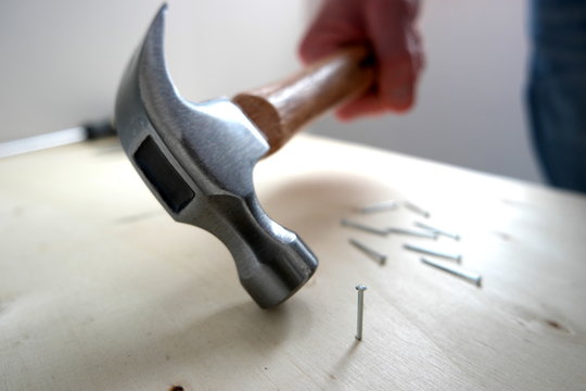 A man picking up a hammer with nails and screws on home improvement construction site