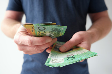 A man counting hundred and fifty Australian dollar bills in cash on hand as payment, savings,...