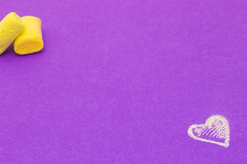 Marshmallows and heart on violet background