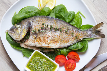 Baked Dorado with spinach and pesto sauce. Close-up. Selective focus.