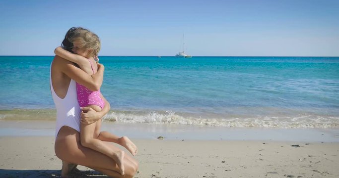 The best moments, the mother with a little daughter are played on the sea, in sunglasses, in swimsuit, rest in beautiful weather, sea and sand background. Concept: love, lifestyle, children, vacations