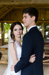 A beautiful married couple in wedding dresses, posing for a photo shooting in an belarusian village. Green background