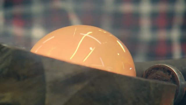 the red-hot glass is spinning on a stick