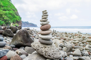 Column of balanced stones on the rocky shore of the ocean on the Hawaiian island