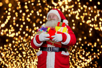 Portrait of happy Santa Claus with gifts. Joyful Santa Claus with a pile of presents on New Year festive background.