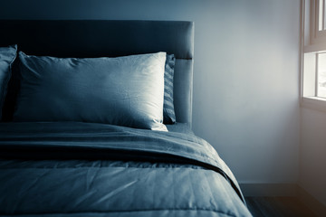 Bed maid-up with clean white pillows and bed sheets in beauty room. Close-up. Lens flair in sunlight.