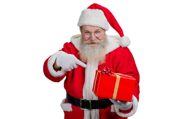 Santa Claus with red gift box. Kind Santa Claus holding Christmas gift and pointing on it with index finger while standing on white background.