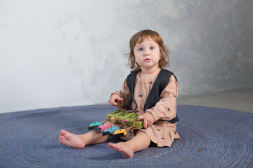 Naklejka premium Little happy girl playing with toy on floor. Kindergarten.