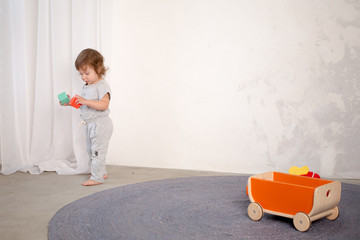 Naklejka premium Little happy girl playing with toy on floor. Kindergarten.