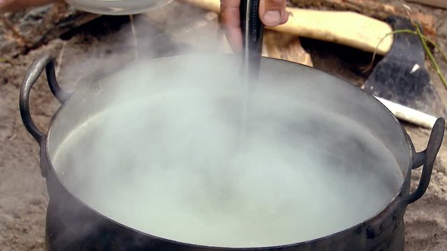 A hand stirs a ladle of fish soup