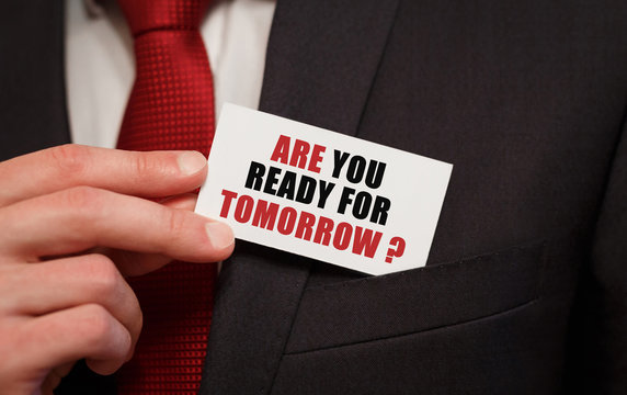 Businessman putting a card with text ARE YOU READY FOR TOMORROW in the pocket