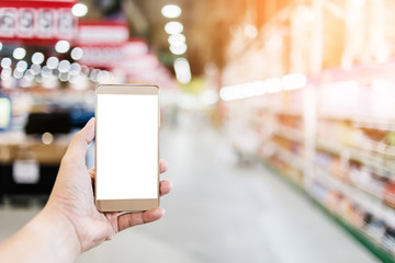hand use smartphone with blur background of supermarket