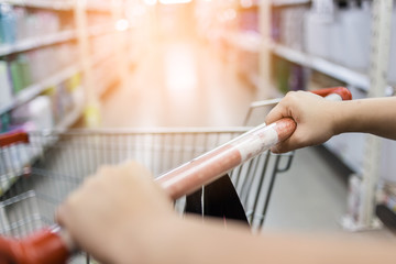 woman hand hold shopping cart in supermarket