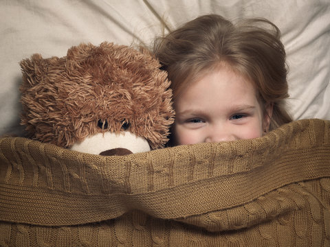 Child And Toy Bear Under Blanket In Bed