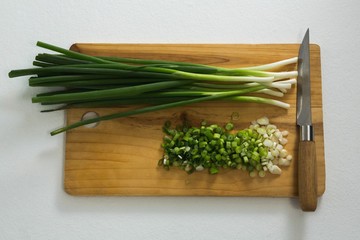 Chopped scallions with knife on chopping board