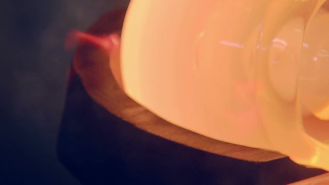 the red-hot glass is spinning on a stick