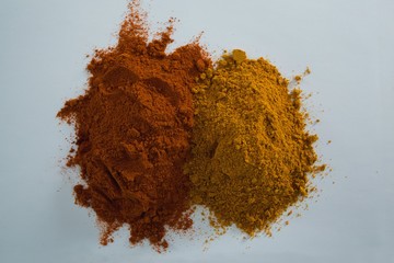 Cinnamon powder and curry powder on white background