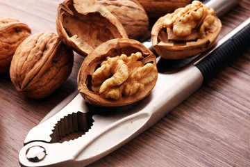Walnut kernels and whole walnuts on brown wooden table.