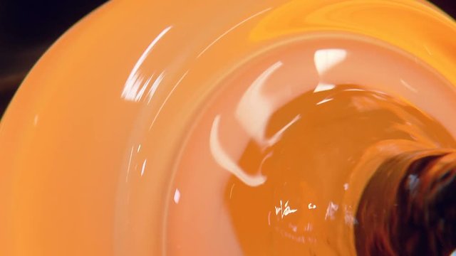 the red-hot glass is spinning on a stick