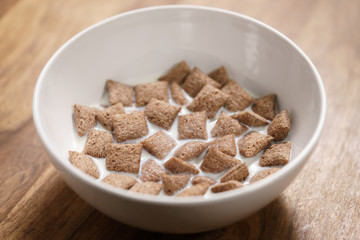 poured with milk chcolate cereal pillow in white bowl on table