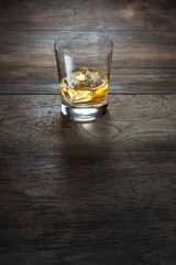 close up view of  glass with ice and whiskey on wooden background