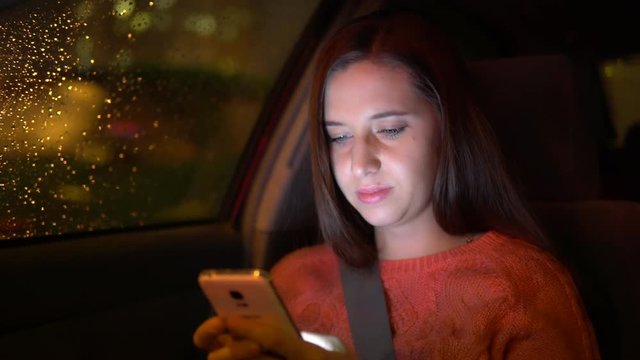 A woman writes an SMS message on the smartphone in the car.