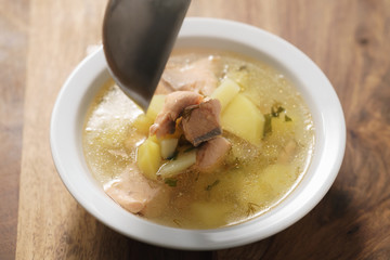 closeup pour fish soup with trout into bowl