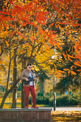 The young musician plays bass ukulele on the street. Man sitting on the ground with guitar. Concept. Basking