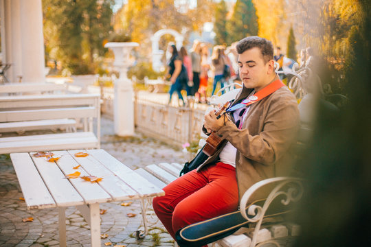 Portrait handsome man playing bass ukulele in the park,Music concept