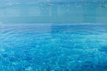 swimming pool water surface infinity edge on top of hotel by the sea