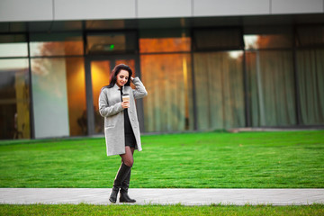 Fototapeta premium Coffee on the go. Beautiful young woman holding coffee cup and smiling while walking along the street
