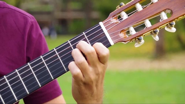 Mann spielt Konzertgitarre im Freien, im Park, Outdoor: linke Hand Gitarrengriff