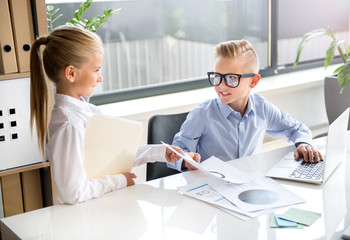 Cheerful children are acting as business people