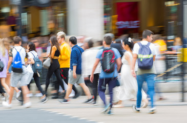 Piccadilly circus with lots of people, tourists and Londoners crossing the junction. Red bus at the background. Blurred type image. London, UK