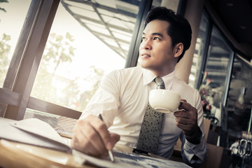 asian smart business man with coffee and newspaper morning time in coffeeshop